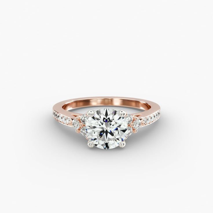 a rose gold engagement ring with two round diamonds on the band and an oval diamond in the center