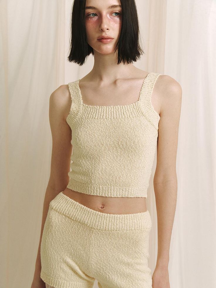 This product is a crop knit sleeveless top that offers a contemporary and cozy addition to any wardrobe with its textured fabric and cropped cut. The piece is designed for a snug fit that highlights the waist, making it an excellent partner to high-waisted bottoms. - The top features a delicate knit pattern that adds a touch of elegance to the simple silhouette.- Its cropped length is on-trend, perfect for pairing with various high-waisted garments.- The sleeveless design makes it ideal for layering under jackets or wearing alone in warmer weather.- Constructed with comfort in mind, the soft knit material provides a gentle feel against the skin. Fitted Textured Knit Top For Loungewear, Chic Knit Tank Crop Top, Fitted Knit Tank Crop Top, Fitted Tank Knit Crop Top, Seamless Cropped Knit Top, Cropped Knit Top For Loungewear, Fitted Knit Crop Top In Beige, Seamless Cropped Knit Tank Top, Chic Textured Knit Fitted Tank Top