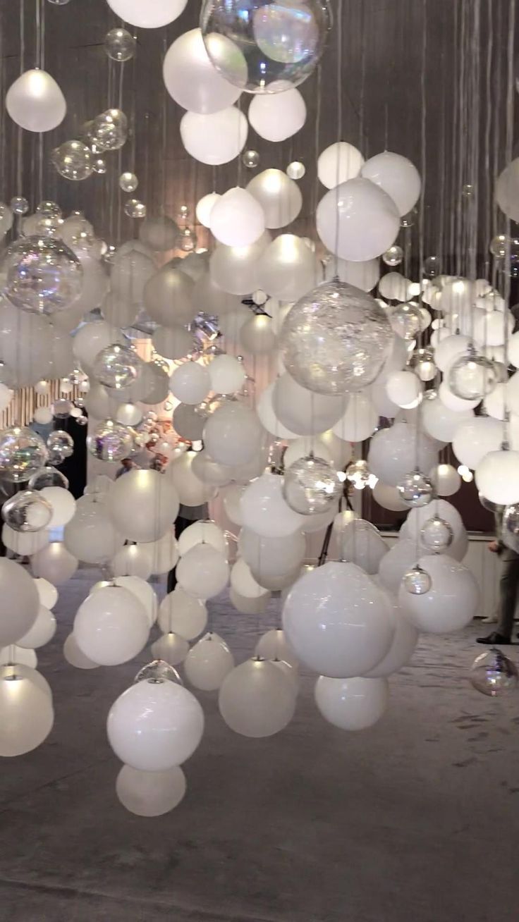 a room filled with lots of white balls and chandeliers hanging from the ceiling