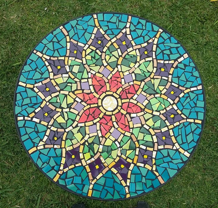 a colorful mosaic table sitting on top of green grass