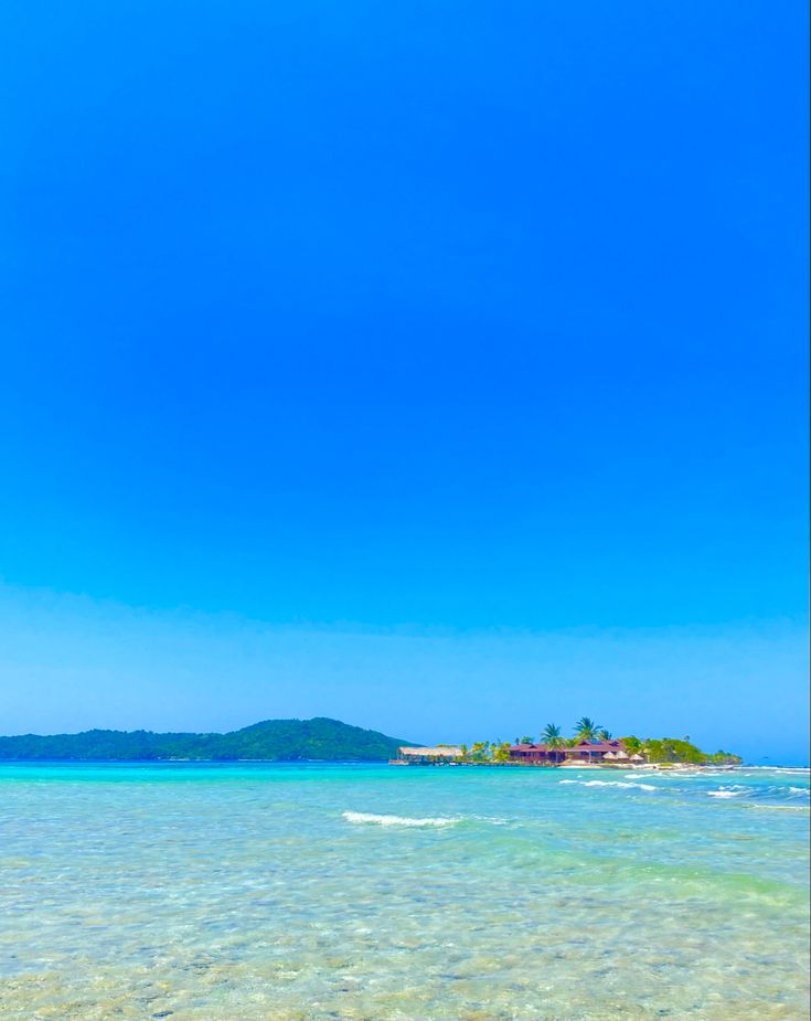 a boat floating on top of the ocean next to a sandy beach with clear blue water