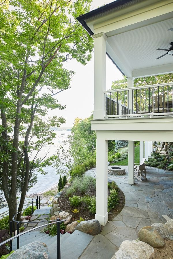 a white house with a porch and stairs leading up to the front door that leads into the water