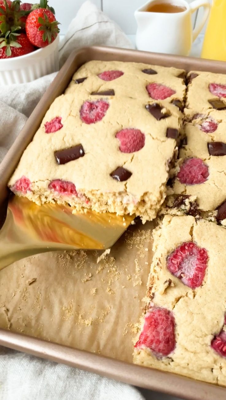 a pan filled with cookies and raspberries on top of a table