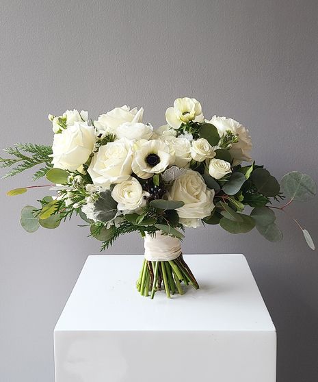 a bouquet of white flowers sitting on top of a white cubed table next to a gray wall