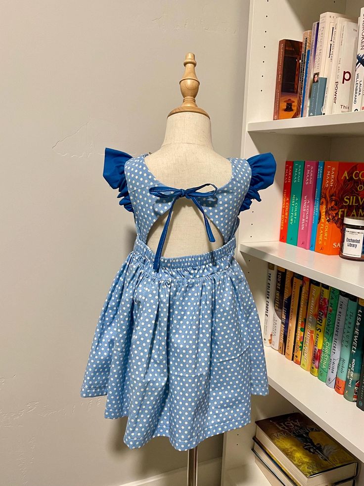 Pictured size 3T This dress features a chargming blue poka dot pattern, flutter sleeves, and an open-back desgin with a bow tie detail. Perfect for any special occasion or everday wear. This dress was crafted by using Peony Patterns Blue Dress With Tie Back And Ruffled Straps, Fitted Flutter Sleeve Twirl Dress For Dress-up, Blue Dress With Smocked Back And Ruffled Straps, Blue Flutter Sleeve Dresses For Dress-up, Blue Ruffled Twirl Dress For Dress-up, Blue Twirl Dress With Ruffles For Dress-up, Blue Ruffled Short Sleeve Twirl Dress, Blue Short Sleeve Twirl Dress With Ruffles, Blue Twirl Dress With Ruffles And Short Sleeves