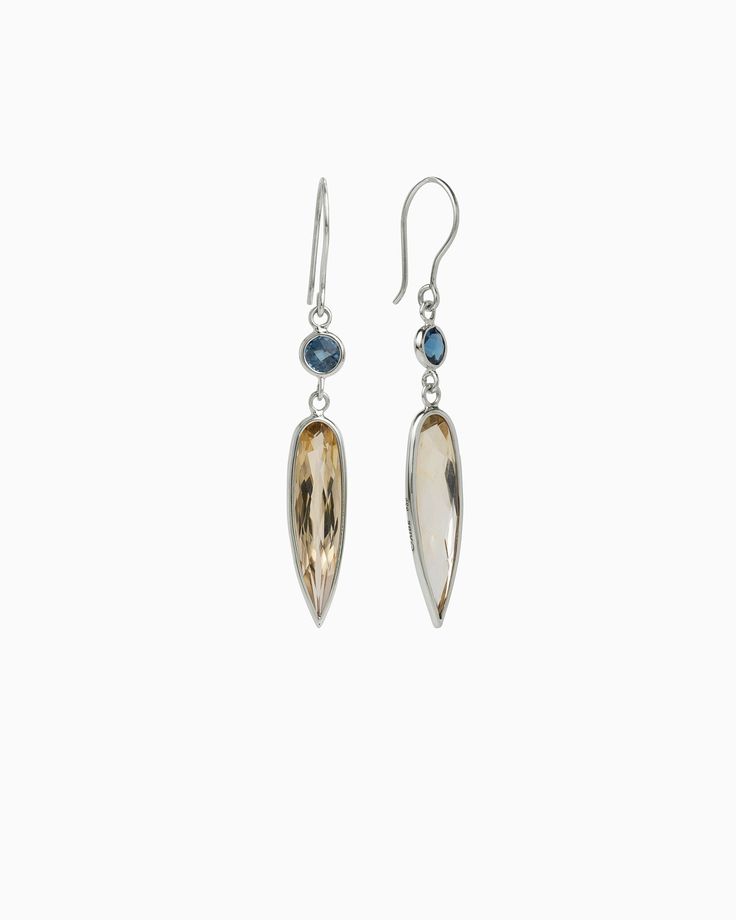 Vibe's beautifully handcrafted Ellipse Stone Drop Earrings are a stunning pair of earrings to add to your collection. These elegant earrings are handcrafted from sterling silver and featuring a round faceted london blue topaz and ellipse shaped faceted citrine. Metal: Sterling silver Stone: London blue topaz, citrine Measurements: 53mm x 10mm Style #: E206LbC Silver Briolette Earrings For Evening, Sterling Silver Drop Earrings With Gemstone Accents, Oval Sterling Silver Earrings For Evening, Sterling Silver Earrings With Gemstone Accents For Formal Occasions, Sterling Silver Gemstone Earrings For Formal Occasions, Formal Sterling Silver Earrings With Gemstone Accents, Polished Topaz Jewelry, Formal Sterling Silver Gemstone Earrings, Elegant Dangle Topaz Jewelry