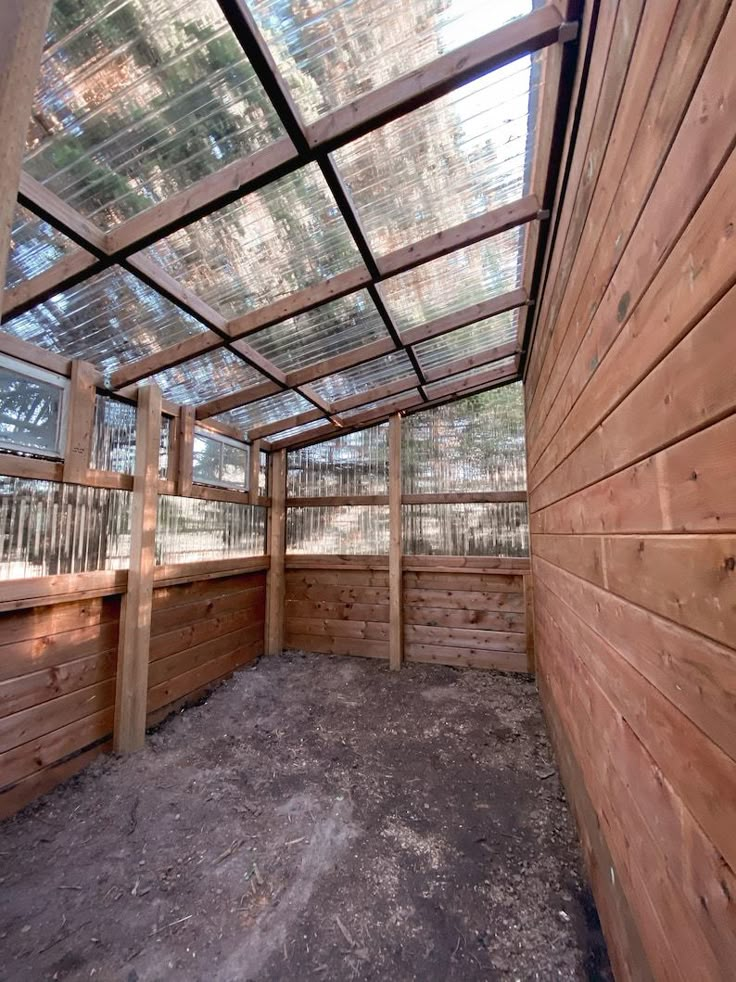 the inside of a building with wooden walls and glass roof, surrounded by wood planks