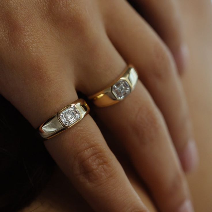 a woman's hand with two gold rings on it and a diamond in the middle