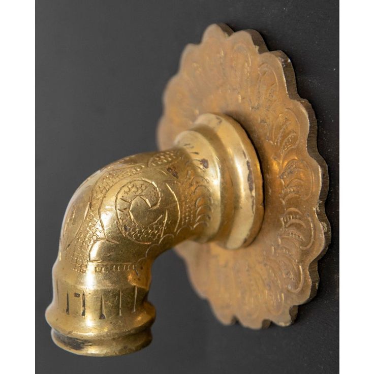 an antique brass door handle on a black wall