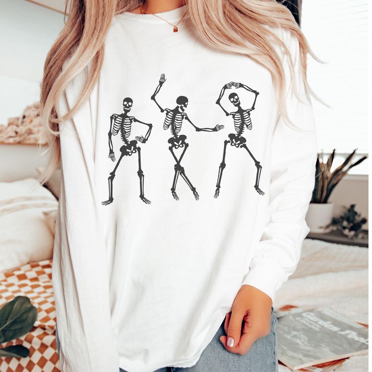 Get ready to be OBSESSED with your new Dancing Skeletons shirt. It's the cutest and most trendy way to emit all those Spooky Season vibes! This is the perfect retro Halloween t-shirt! Crafted from the softest fabric, this Comfort Colors long sleeve tee ensures the utmost comfort throughout the day. * Q U I C K F A C T S * ✺ 100% preshrunk cotton ✺ Wash and dry on delicate, inside out (on cool for best results) * S I Z I N G * ✺ Models are wearing size Large ✺ Sizing is unisex so runs like men's, Trendy Skull Shaped Tops For Fall, Trendy Skull Tops For Halloween, Trendy Skull Shaped Tops For Halloween, Fall Skull Print Long Sleeve T-shirt, Relaxed Fit Skull Print Top For Halloween, Long Sleeve Skull Print T-shirt For Fall, Long Sleeve Graphic Tee With Skull Print, Halloween Long Sleeve T-shirt With Skull Print, Halloween Long Sleeve Relaxed Fit T-shirt