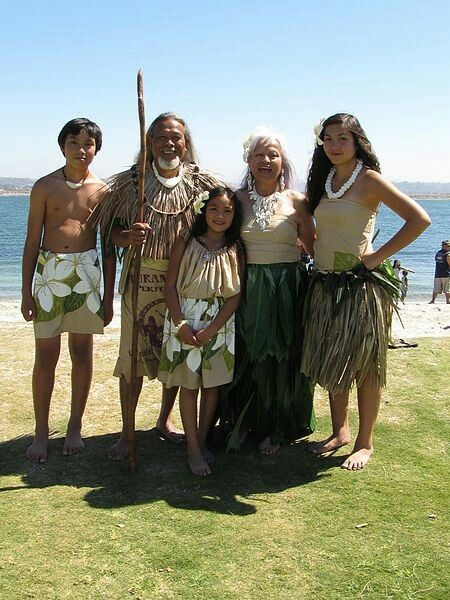 a group of people standing on top of a lush green field next to the ocean