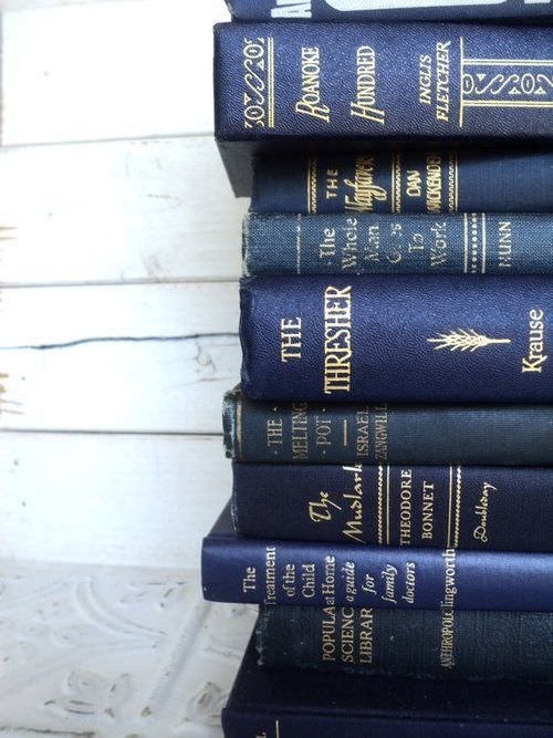 a stack of black books sitting next to each other on top of a wooden table