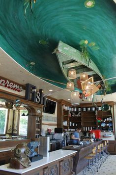 the interior of a restaurant with an artistic ceiling painted like a boat and lights hanging from the ceiling