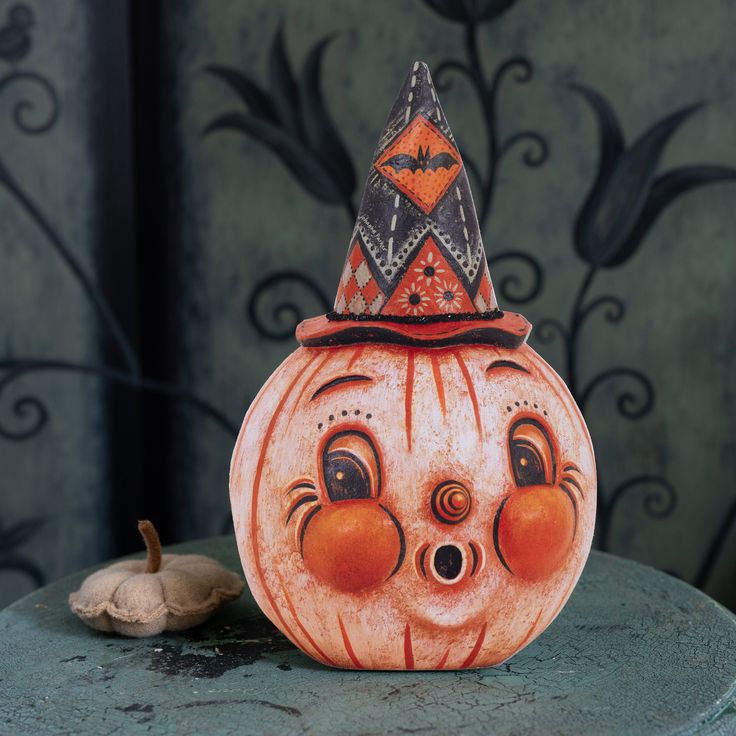 a ceramic pumpkin with a hat on it's head