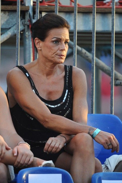 two women sitting next to each other in the stands at a sporting event, one wearing a black tank top