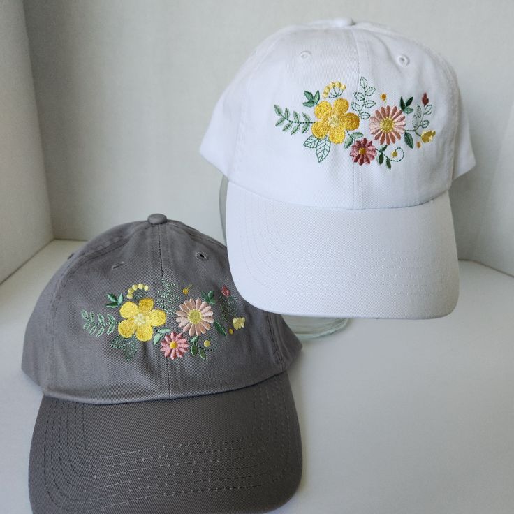 two hats sitting next to each other on top of a white table with flowers painted on it