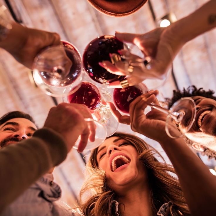 a group of people toasting with wine glasses in front of their heads and hands