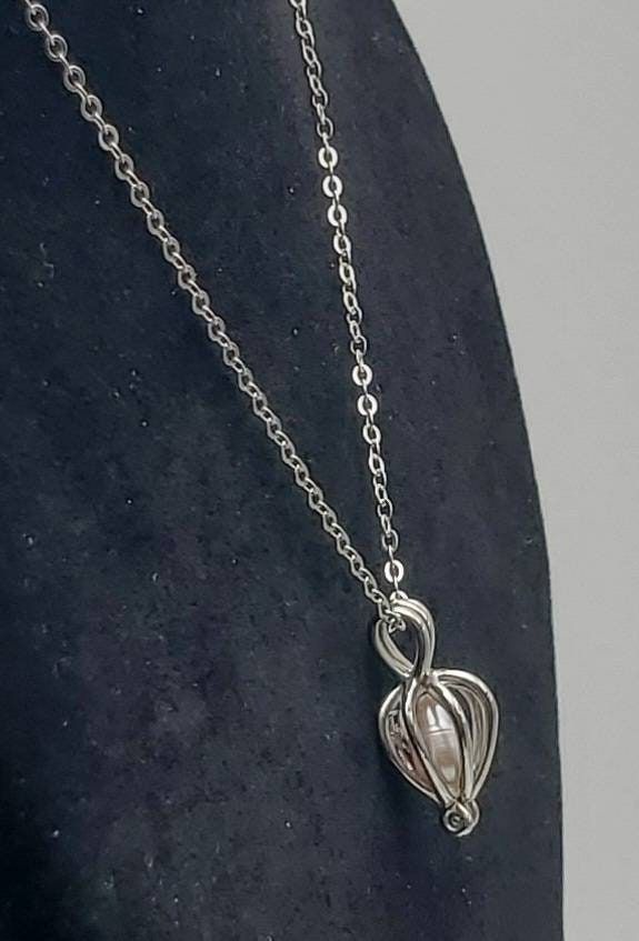 Nice pink pearl, loose within a silver tone metal hinged cage pendant in a vaguely heart shape. The pendant is hung on a sterling silver rolo link chain necklace. Pendant 7/8 x 7/16 x 3/8" 2.4g UNMARKED Chain 16 1/2 inches long 1.2g Marked "925" Elegant Silver Heart Necklace In Stainless Steel, Elegant Silver Stainless Steel Heart Necklace, Silver Heart Pendant With Pearl, Silver Heart-shaped Pearl Pendant Jewelry, Silver Heart Pendant Jewelry With Pearl, Elegant Nickel Free Metal Heart Necklace, Elegant Nickel-free Metal Heart Necklace, Elegant Nickel Free Heart Necklace, Elegant Silver Heart Necklace With Lobster Clasp