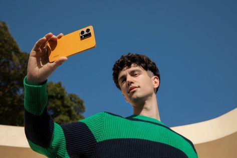 a man taking a selfie with his cell phone in the air while wearing a green and black sweater