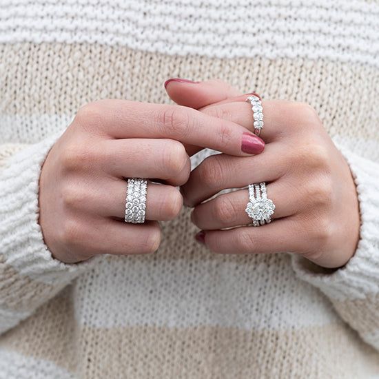 the woman is wearing two rings on her fingers and one ring has three diamonds in it