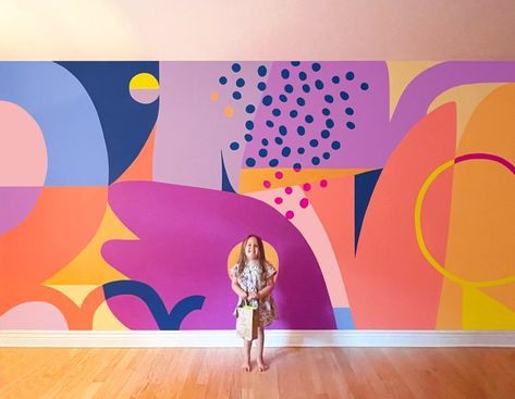 a woman standing in front of a colorful wall