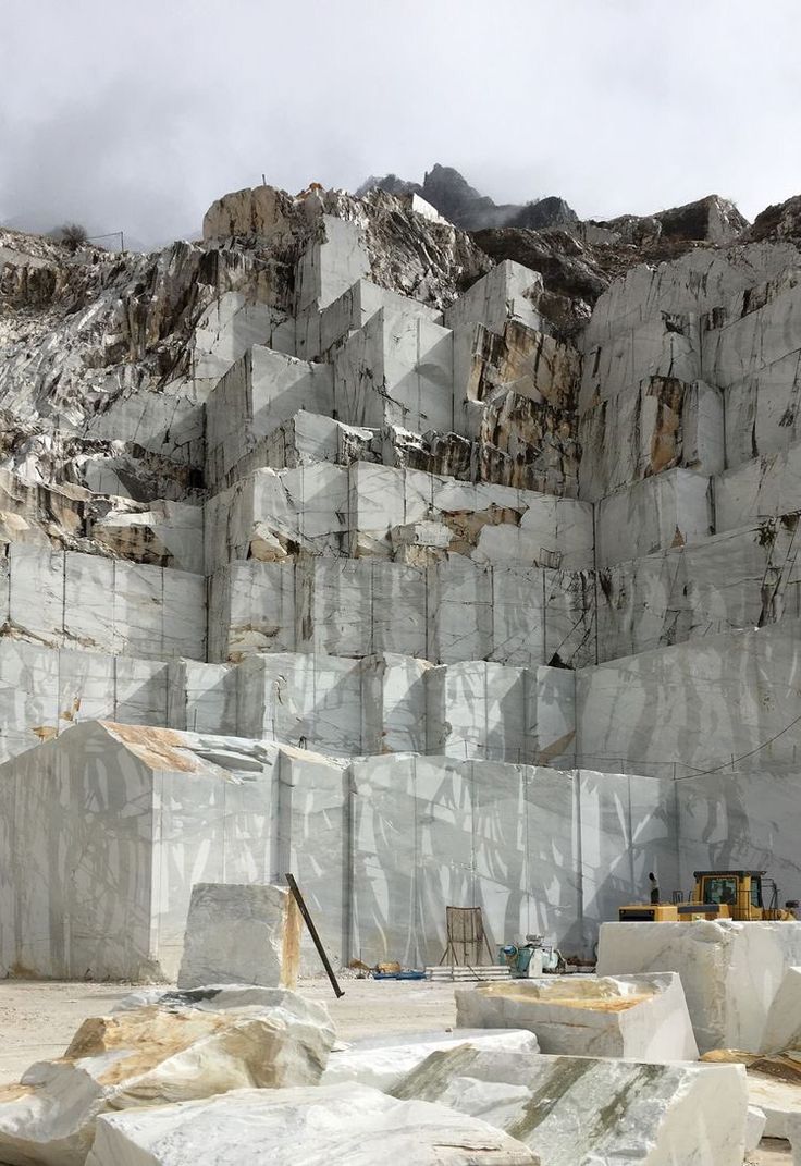 large white rocks are stacked on top of each other in front of a rocky mountain