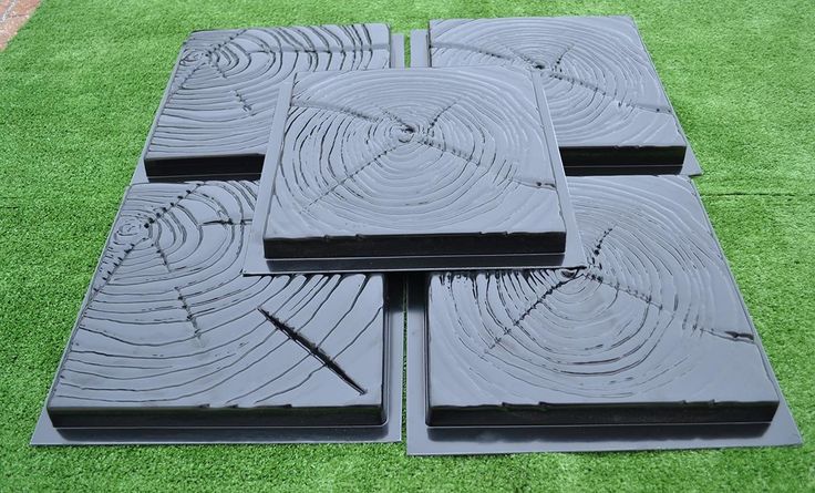 four pieces of black plastic sitting on top of green artificial grass in the shape of squares