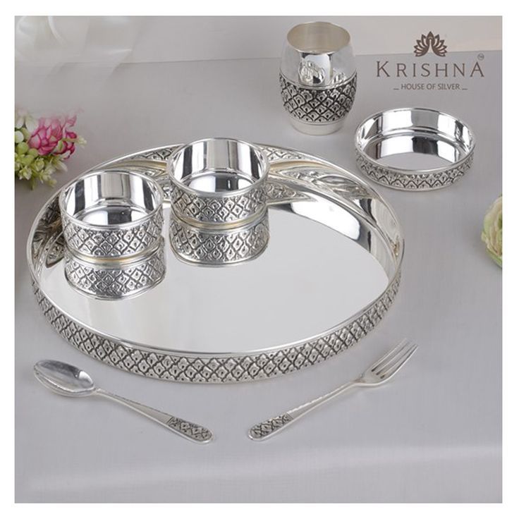 a silver tray with four cups and spoons on it, next to a flower