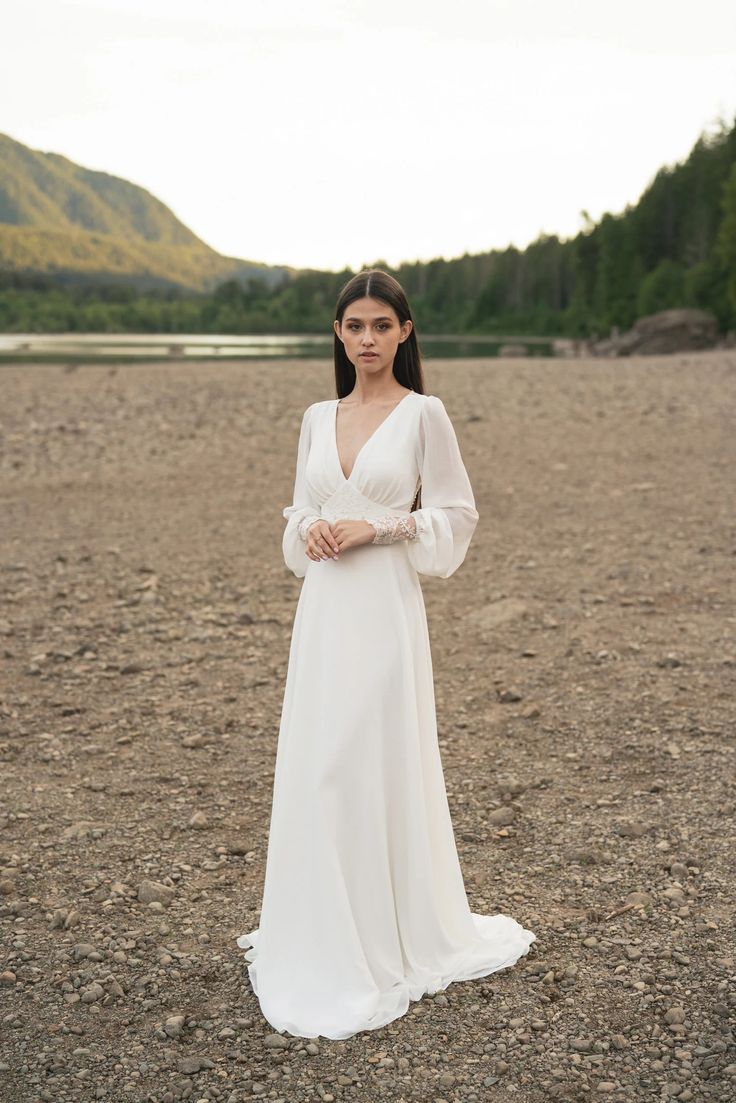 a woman wearing a white dress standing in an empty field