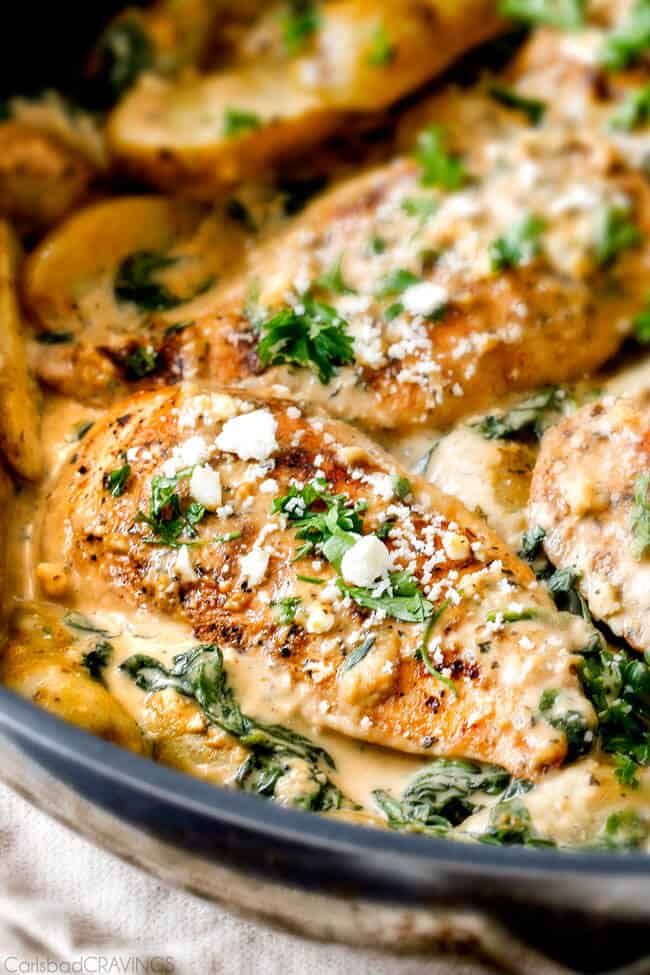 a pan filled with chicken and spinach covered in cheese