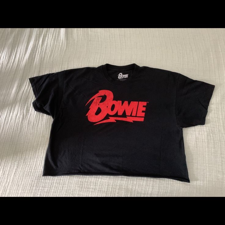 a black t - shirt with the word bomb on it sitting on top of a bed