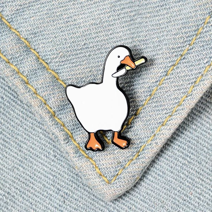 a white duck pin sitting on top of a blue jean shirt with yellow pins in it's chest