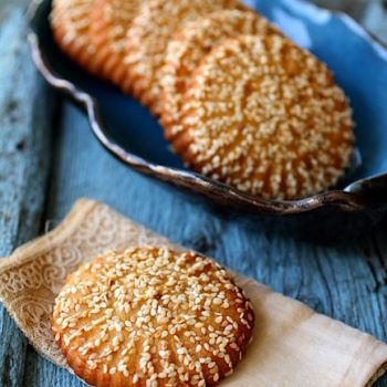 two sesame seed cookies on a wooden table