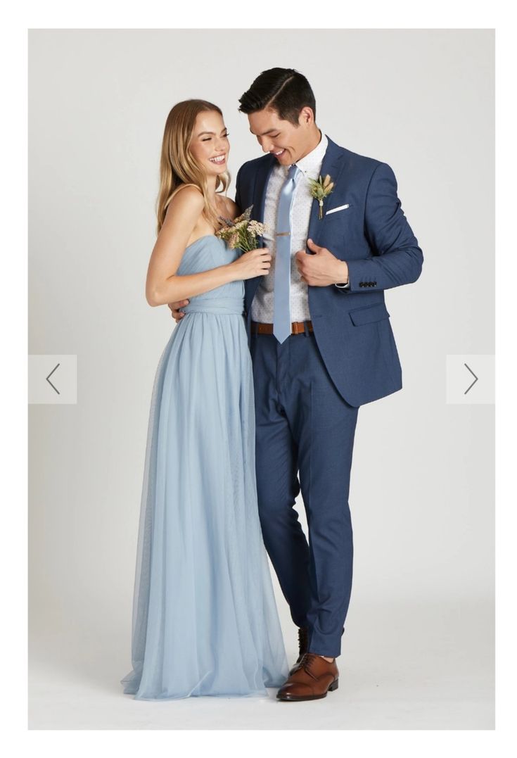 a man in a blue suit standing next to a woman wearing a light blue dress