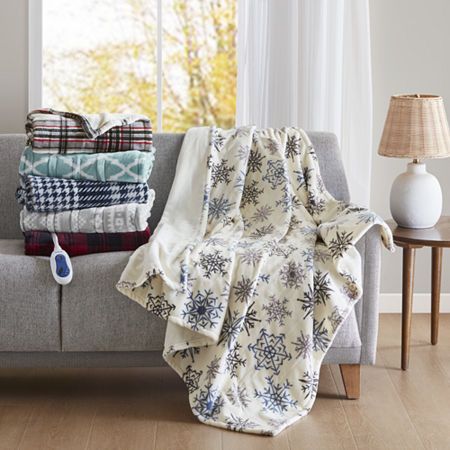 a couch covered with blankets and pillows in front of a window