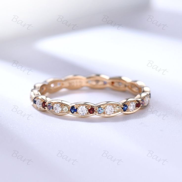 a gold ring with multicolored stones on the inside and outside, sitting on a white surface