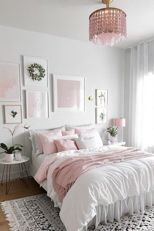 a white bedroom with pink accents and pictures on the wall above the bed, along with a chandelier