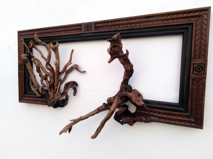 an old frame with some branches hanging on it and another piece of driftwood sticking out of the frame