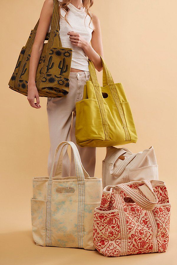 a woman standing next to three purses and bags in different colors on a beige background