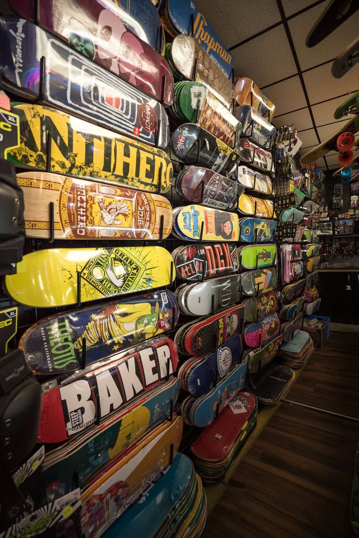 there are many skateboards on display in the store, all stacked up against the wall