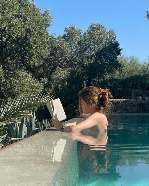 a woman reading a book by the pool