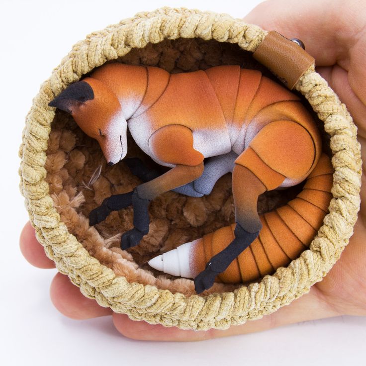 a hand holding a small toy animal in a basket with other items inside it,