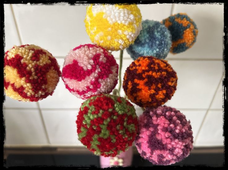 multicolored crocheted balls are arranged in a vase on the counter top