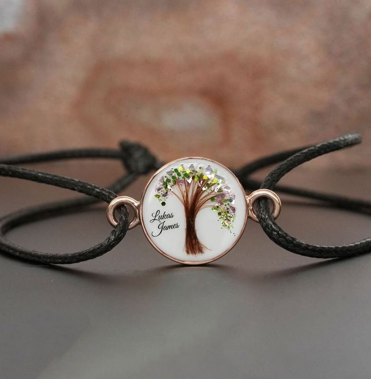 "Breastmilk \"Tree of Life\" disc bracelet with baby hair and birth color flakes and shimmers, baby name, date. Yellow or Rose Gold plating over 925 sterling silver cup and waxed cord. Our \"Tree of Life\" bracelet  transforms your breast milk into a beautiful keepsake . A simple, tasteful 14mm circle filled with your breastmilk. We can put a lock of hair from one child or from two or three of your children.  For all our breast milk Tree of Life collection, please visit: https://www.etsy.com/ca/ Adjustable Rose Gold Jewelry With Birth Flower, Adjustable Jewelry With Tree Of Life Round Pendant, Adjustable Round Pendant Jewelry With Tree Of Life, Adjustable Tree Of Life Round Pendant Jewelry, Adjustable Round Pendant With Tree Of Life, White Adjustable Nature-inspired Jewelry, Personalized Adjustable Nature-inspired Jewelry, White Tree Of Life Jewelry Gift, Handmade Rose Gold Jewelry For Keepsake