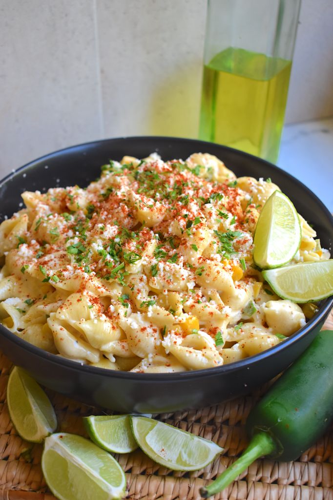 a bowl filled with macaroni and cheese next to sliced green peppers