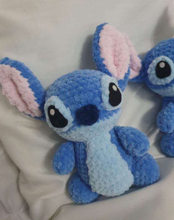 two small stuffed animals sitting on top of a bed