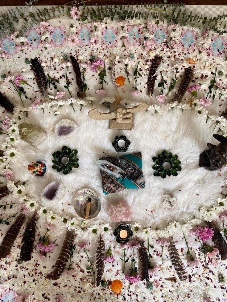 an arrangement of flowers, feathers and other items on a white tablecloth covered in fake fur