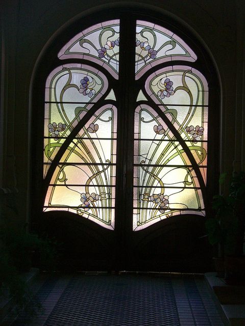 a large stained glass window in the center of a building with an arched door and sidelight