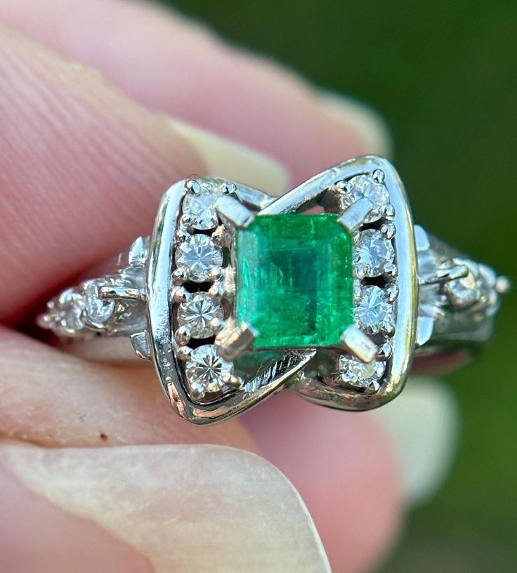 Elevate your jewelry collection with this very unique Vintage Emerald and Diamond Art Deco Style Ring--an exquisite fusion of timeless elegance and Art Deco glamour. This ring is a testament to the opulence of a bygone era, featuring a lush emerald at its center, surrounded by a dazzling array of diamonds, all set in a meticulously crafted Art Deco-inspired design.  Natural emerald weighing .44 carats Natural Diamonds weighing .15 carats.  Size: 6.5 The emerald, with its rich green hue, is a captivating focal point, symbolizing renewal and prosperity. Surrounding this vibrant gemstone are carefully arranged diamonds, adding brilliance and sophistication to the piece. The geometric patterns and intricate detailing of the Art Deco style setting enhance the ring's vintage allure, making it a Heirloom Emerald Diamond Ring For Formal Events, Elegant Gia Certified Emerald Cluster Ring, Luxury Emerald Cut Emerald Cluster Ring, Formal Diamond Ring With Prong-set Emeralds, Luxury Platinum Cluster Emerald Ring, Luxury Emerald Cluster Ring With Center Stone, Timeless Emerald Anniversary Ring, Platinum Emerald Ring In White Gold, Timeless Emerald Wedding Anniversary Ring