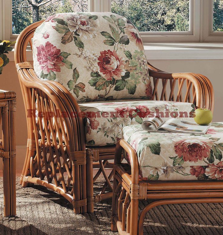 a wicker chair and ottoman in front of a window with flowers on the cushion